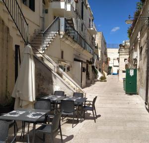 un callejón vacío con mesas, sillas y una sombrilla en Casa Vacanza Martino en Matera