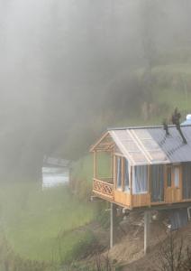 a tiny house on a hill in the fog at Cloudwalk Treehouse in Jibhi