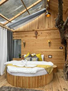 ein Schlafzimmer mit einem großen Bett an einer Holzwand in der Unterkunft Cloudwalk Treehouse in Jibhi