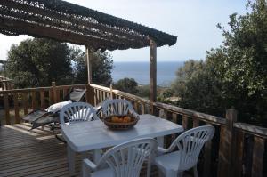 una mesa y sillas en una terraza de madera con vistas al océano en chez Jean-Marc en Lumio