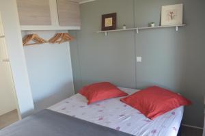 a bed with two red pillows in a room at chez Jean-Marc in Lumio