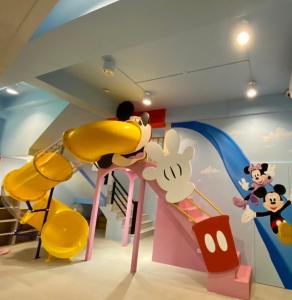 高雄親子溜滑梯High Fun旅店 في كاوشيونغ: غرفة مع منطقة لعب مع شريحة فأر ميكي