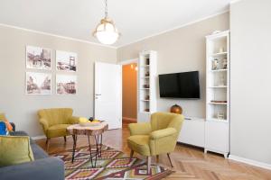 ein Wohnzimmer mit 2 Stühlen und einem TV in der Unterkunft Central Park Apartments in Belgrad