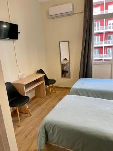 a hotel room with two beds and a desk and a window at Hotel Kastoria in Thessaloniki