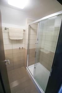 una doccia con porta in vetro in bagno di VÁRLAK VENDÉGHÁZ Apartman 2 a Siófok