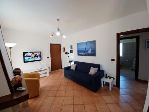 sala de estar con sofá azul y TV en Villa Giulia - Giungano - Cilento en Giungano