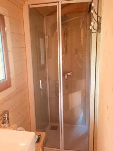 uma cabina de duche em vidro na casa de banho com um lavatório em Roulotte Un temps pour soi em Bérat