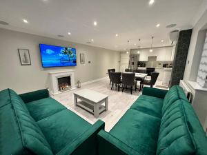 a living room with a green couch and a fireplace at Luxury House in Greenford