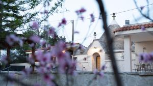 una iglesia detrás de una valla con flores púrpuras en Trulli Magnolia en Putignano