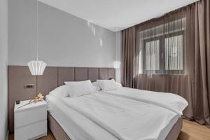 sypialnia z dużym białym łóżkiem i oknem w obiekcie Apartmani Vila Jelena 1 w Makarskiej