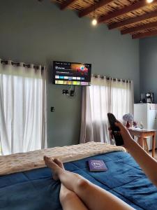 a person laying on a bed with their feet on a television at Chalé Morro Grande in Paraisópolis