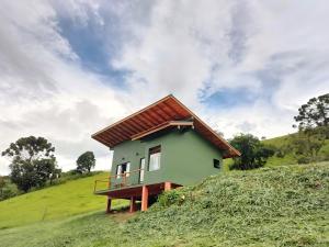 a small house on top of a grassy hill at Chalé Morro Grande in Paraisópolis