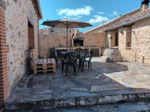 een patio met een tafel en stoelen en een parasol bij El Refugio de la Esquina in Mata de Quintanar