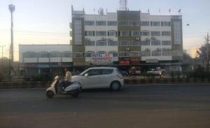 a white car and a person on a scooter in front of a building at Hotel KK Residency in Nagpur