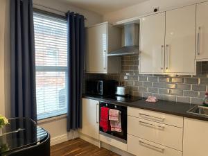 a kitchen with white cabinets and a black counter top at Harvey Apartments in Derry Londonderry