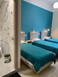 three beds in a room with blue walls at Hotel Kastoria in Thessaloniki