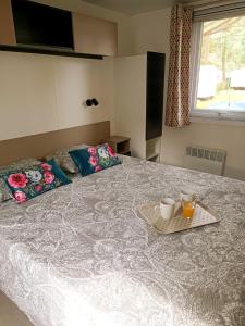 a bed with a tray with two cups on it at Océan Mobilhome Siblu Bonne Anse Village Vacances La Palmyre in Les Mathes