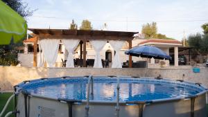 a swimming pool with an umbrella in front of a house at Trulli Magnolia in Putignano