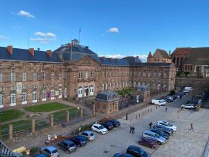 un grand bâtiment avec des voitures garées dans un parking dans l'établissement La Mezzanine des Rohan Saverne, à Saverne