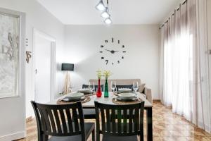 a dining room with a table and a clock on the wall at Appartamento Dada in Carmiano