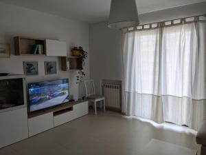 een woonkamer met een televisie en een raam bij La Casa dei Due Mari - large apartment with parking in Taranto