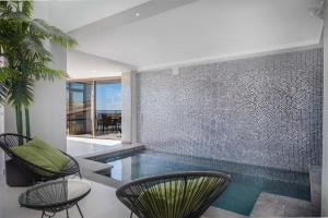 een binnenzwembad met stoelen en een tegelmuur bij Villa Selene heated Indoor Pool in Costa Calma