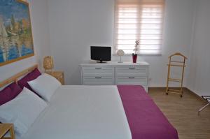 een slaapkamer met een wit bed en een televisie bij Peppe's house in Gravina di Catania