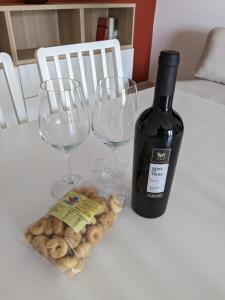 a bottle of wine and two wine glasses on a table at La Casa dei Due Mari - large apartment with parking in Taranto