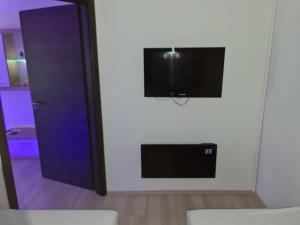 telewizor z płaskim ekranem na białej ścianie w pokoju w obiekcie Smaragd apartman w mieście Pecz