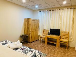 a room with two beds and a desk with a television at Mystic Vibes - Jibhi in Jibhi