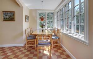 a dining room with a table and chairs and windows at Nice Home In Nexø With Wifi in Neksø