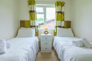 two twin beds in a room with a window at Conkers Retreat at Finlake Resort & Spa, Devon in Chudleigh