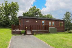 a small cabin with a deck on a grass field at Conkers Retreat at Finlake Resort & Spa, Devon in Chudleigh