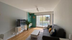 uma sala de estar com um sofá e uma televisão em LE CYLIA em Mérignac