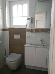 ein Badezimmer mit einem WC, einem Waschbecken und einem Spiegel in der Unterkunft Pension Eule in Sankt Kanzian am Klopeiner See