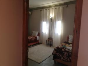 a small room with two beds and a mirror at Riad Ouinz in Aït Benhaddou