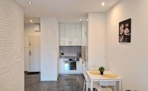 a kitchen with white cabinets and a table and chairs at Apartament Czechowska Comfort in Lublin