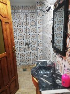 a bathroom with a black toilet and a wall at Riad Ouinz in Aït Benhaddou