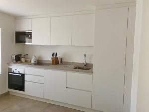 a white kitchen with white cabinets and a sink at Le Levant: logement dans ancienne batisse de 1718 in Cudrefin