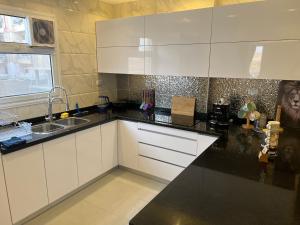 a kitchen with white cabinets and a black counter top at Pyramids View Apartment in Giza