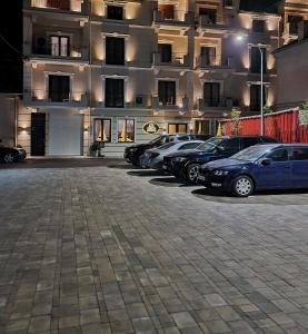 a parking lot with cars parked in front of a building at Legacy Boutique Hotel in Korçë