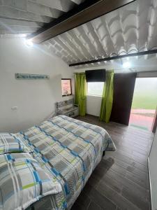 a bedroom with a bed in a room with green curtains at Confortable cabaña para que disfrute con su pareja in Santandercito