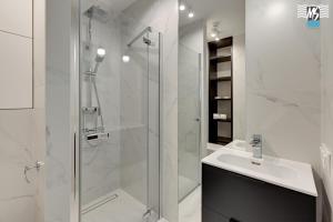 a white bathroom with a shower and a sink at MS Apartments Rest 5.0 in Sopot