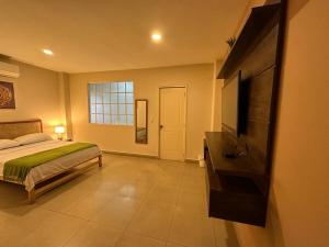 a bedroom with a bed and a flat screen tv at El Patio Suites in Guayaquil