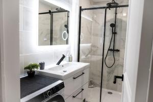 y baño blanco con lavabo y ducha. en Appartement rénové - wifi - jardin - centre de Niort, en Niort