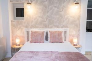 a bedroom with a white bed with two lamps at Appartement rénové - wifi - jardin - centre de Niort in Niort