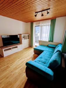 a living room with a blue couch and a television at Apartments Zakrasnik in Škofja Loka