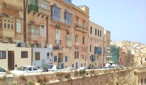 una strada cittadina con auto parcheggiate davanti agli edifici di Tide 21 Savynomad Harbour Residences Valletta a La Valletta