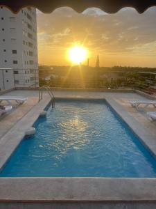 einen Pool mit Sonnenuntergang im Hintergrund in der Unterkunft Bellomar I Exclusive Juan Dolio Playa Hemingway in Juan Dolio