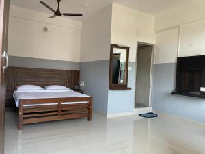 a bedroom with a bed and a mirror and a television at SERENITY GREENS in Madikeri